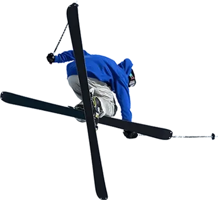 Skier in a dark blue jacket performing an aerial trick by crossing his skis and his back towards the camera.